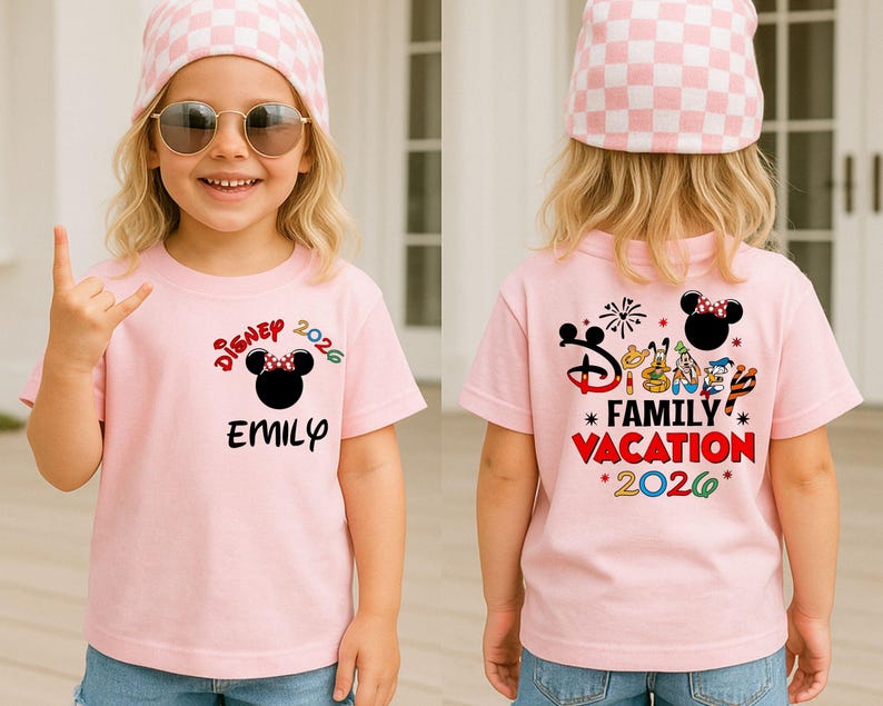 May include: A light pink t-shirt with the text "Disney 2026" and a Minnie Mouse graphic. The front of the shirt has the name "Emily" printed below the graphic. The back of the shirt says "Family Vacation 2026".