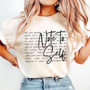 Może przedstawiać: Biały t-shirt z czarnym nadrukiem tekstowym, który brzmi "Note to Self" i zawiera motywacyjny przekaz o miłości do siebie i poczuciu własnej wartości.