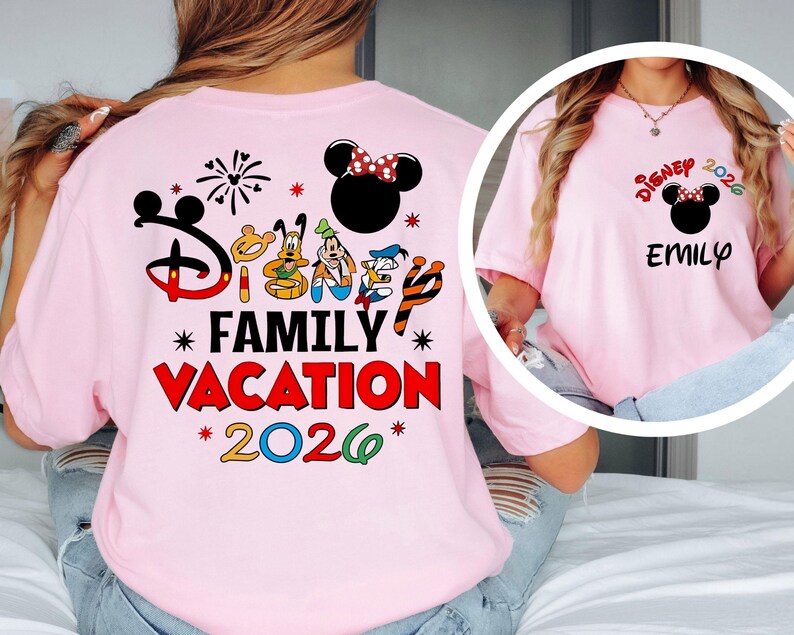 May include: A light pink t-shirt featuring a Disney Family Vacation design. The back of the shirt has a large graphic with the Disney logo, characters, and the words "Family Vacation 2026." The front of the shirt has a smaller design with a Minnie Mouse head and the name "EMILY."