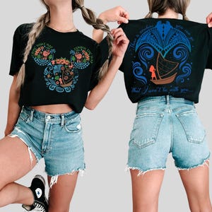 Puede incluir: Camiseta negra con un dise&ntilde;o gr&aacute;fico colorido. El dise&ntilde;o frontal es una cabeza de Mickey Mouse con elementos florales y un barco, y el texto "Know the Way". El dise&ntilde;o trasero muestra un barco y un personaje con el texto "There is nowhere you can go that I won't be with you..."