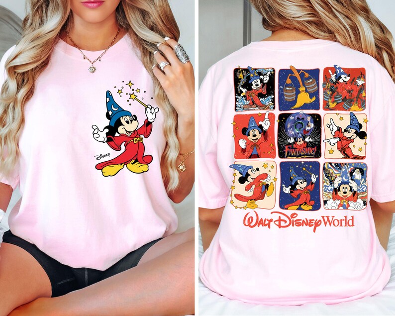 May include: Light pink t-shirt featuring a graphic of Mickey Mouse as a wizard on the front. The back of the shirt displays a grid of Mickey Mouse images and the words "Walt Disney World".