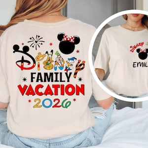 May include: Cream-colored t-shirt featuring a Disney-themed design. The back of the shirt displays the text "Disney Family Vacation 2026" with Mickey Mouse and friends. The front has a smaller design with "Disney 2026" and a name.