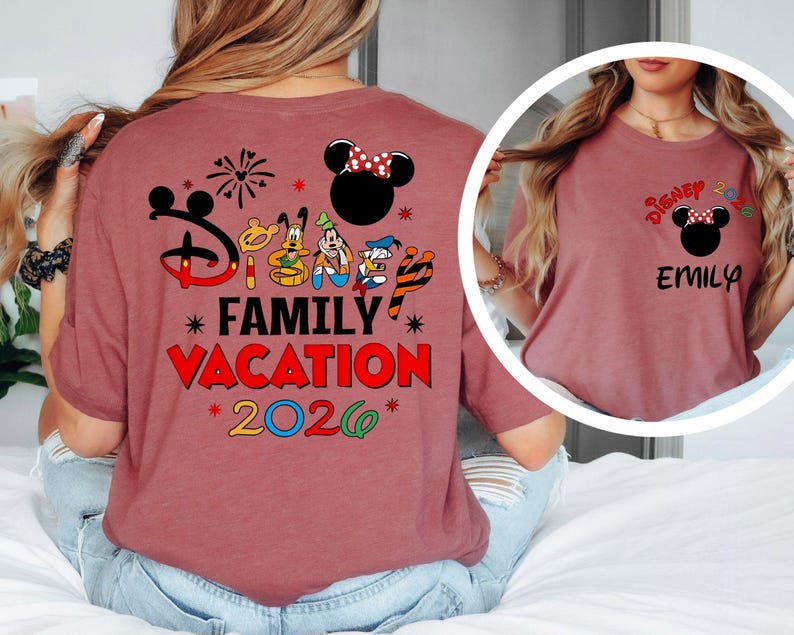 May include: A maroon t-shirt featuring a Disney-themed design. The back of the shirt displays the text "Disney Family Vacation 2026" with Mickey Mouse and friends. The front of the shirt has a smaller design with the name "Emily".