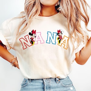 May include: A white t-shirt with the word "NANA" in colorful letters. Mickey Mouse and Minnie Mouse are on either side of the word.