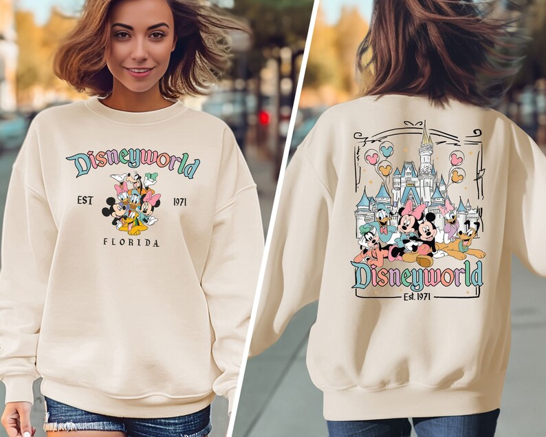May include: A cream-coloured sweatshirt with the text "Disneyworld" and various cartoon characters. The sweatshirt also features the text "EST 1971 FLORIDA". The back of the sweatshirt has a castle graphic and the text "Disneyworld Est. 1971".