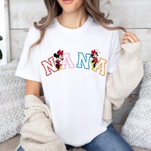 May include: White t-shirt with a colorful "NANA" graphic featuring Mickey Mouse characters.