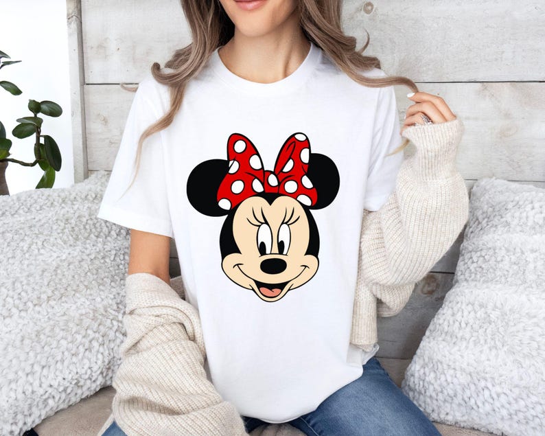 May include: White t-shirt with a black and white cartoon image of Minnie Mouse wearing a red bow with white polka dots.
