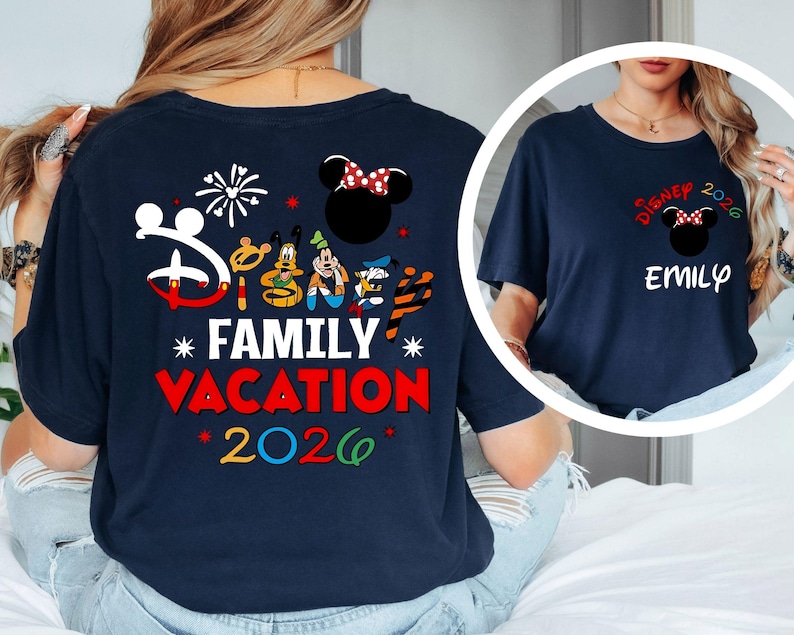 May include: Navy blue t-shirt with a Disney theme. The back features Mickey Mouse, Minnie Mouse, Donald Duck, and Goofy graphics, along with the text "Family Vacation 2026." The front has a smaller design with "Disney 2026" and a name.