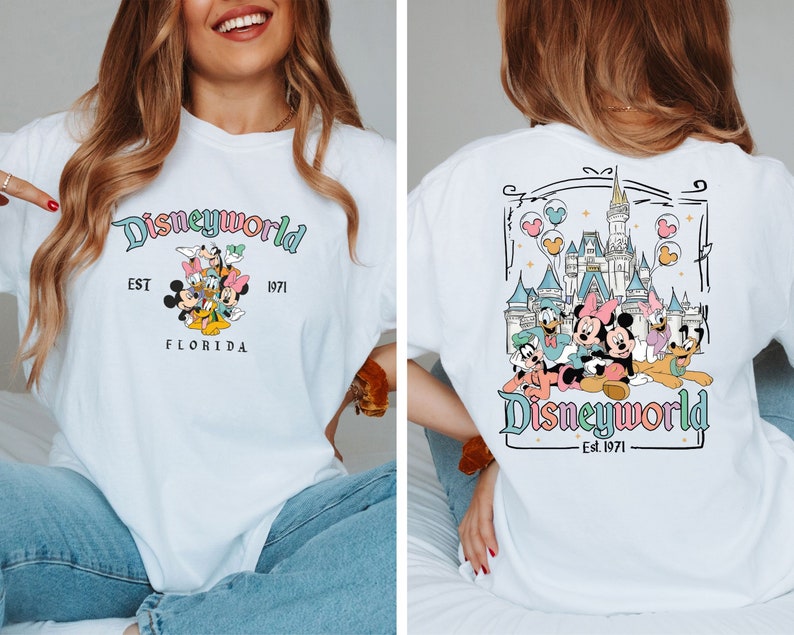 May include: White t-shirt with a Disneyworld design. The front has the text "Disneyworld" in pastel colours, with Mickey Mouse, Minnie Mouse, Donald Duck, Daisy Duck, and Goofy. The back shows the Disney castle and characters.