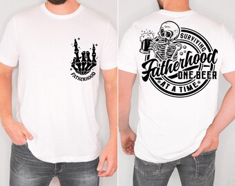 Può includere: T-shirt bianco con grafica nera sulla tasca anteriore raffigurante una mano di scheletro in un gesto rock and roll e la parola "Fatherhood". La parte posteriore della maglietta presenta un disegno circolare con uno scheletro che beve birra e la scritta "Surviving Fatherhood One Beer At A Time".