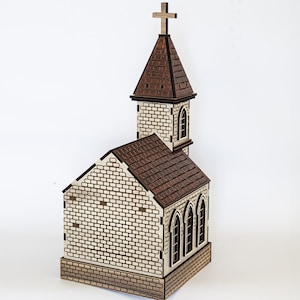 K&ouml;nnte beinhalten: Ein Holzmodell einer Kirche mit einem braunen Dach und einer wei&szlig;en Backsteinfassade. Die Kirche hat einen hohen Turm mit einem Kreuz auf der Spitze. Das Modell ist detailliert mit Fenstern und einer T&uuml;r.