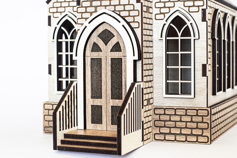 K&ouml;nnte beinhalten: Ein Holzmodell einer Kirche mit einer braunen T&uuml;r, zwei Fenstern und einer Backsteinfassade. Die Kirche hat einen kleinen Vorbau mit Stufen, die zur T&uuml;r f&uuml;hren.