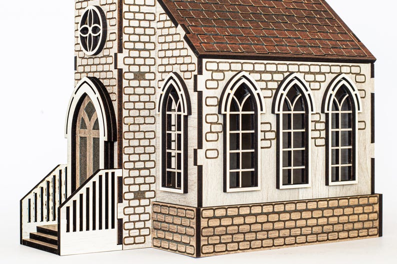 K&ouml;nnte beinhalten: Ein Holzmodell einer Kirche mit einem braunen Dach, wei&szlig;en Backsteinw&auml;nden und schwarzen Verzierungen. Die Kirche hat eine Vordert&uuml;r mit einem Spitzbogen und ein kleines Fenster dar&uuml;ber. Es gibt f&uuml;nf Fenster an der Vorderseite der Kirche, alle mit Spitzb&ouml;gen.