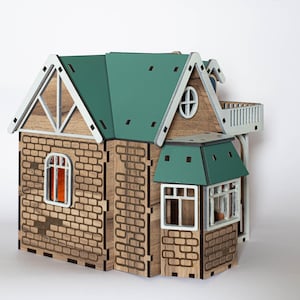 May include: A wooden model house with a green roof, white trim, and brick detailing. The house has multiple windows and a small balcony.