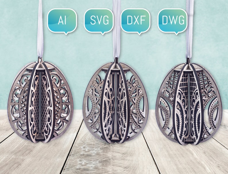 Puede incluir: Tres adornos de madera con forma de huevo con intrincados dise&ntilde;os cortados con l&aacute;ser. Los adornos cuelgan de cuerdas blancas y est&aacute;n etiquetados con los formatos de archivo AI, SVG, DXF y DWG.