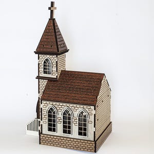 K&ouml;nnte beinhalten: Ein Holzmodell einer kleinen Kirche mit braunem Dach und wei&szlig;en Backsteinw&auml;nden. Die Kirche hat einen Turm mit einem Kreuz auf der Spitze und drei Fenster an der Vorderseite.
