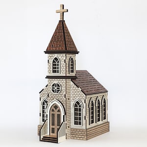 K&ouml;nnte beinhalten: Ein Holzmodell einer Kirche mit braunem Dach, wei&szlig;en W&auml;nden und schwarzen Fenstern. Die Kirche hat ein Kreuz auf dem Dach und eine kleine Veranda mit Stufen.