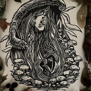 May include: A black and white linocut print on paper featuring a central figure with long flowing hair emerging from a large mushroom cap. The artwork includes clusters of smaller mushrooms, foliage, and the text ONEIROS at the bottom center.