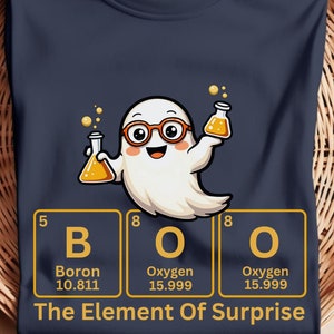 Könnte beinhalten: Ein marineblaues T-Shirt mit einem Cartoon-Geist, der eine Brille trägt und Becher hält. Der Geist steht vor einem Periodensystem mit den Elementen "B" für Bor, "O" für Sauerstoff und "O" für Sauerstoff. Der Text unter dem Periodensystem lautet "The Element Of Surprise".