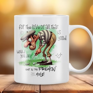 May include: White ceramic coffee mug with a cartoon golfer illustration and the text "for the love of all that is good would you just get in the freakin' hole!"
