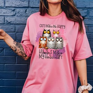 May include: A pink t-shirt with a graphic of cats and the text "Cats Make Me Happy Humans Make My Head Hurt".