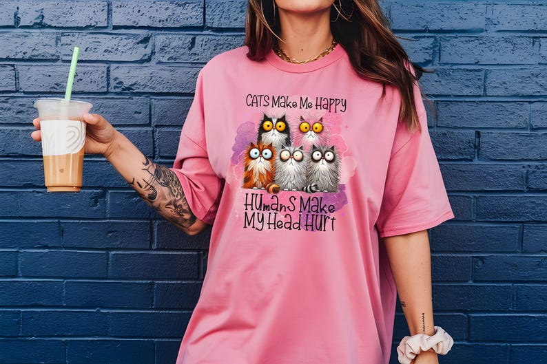 May include: A pink t-shirt with a graphic of cats and the text "Cats Make Me Happy Humans Make My Head Hurt".
