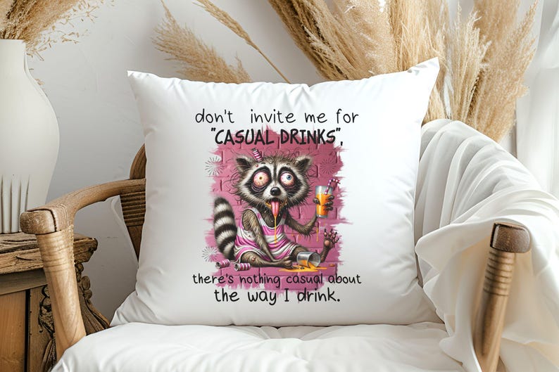 May include: White throw pillow with a humorous illustration of a raccoon drinking from a glass. The text reads "don't invite me for "CASUAL DRINKS", there's nothing casual about the way I drink."