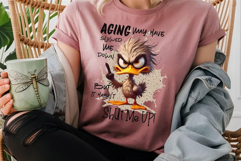 May include: A pink t-shirt with a cartoon duck design and the text "Aging may have slowed me down, but it hasn't shut me up!"