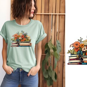 K&ouml;nnte beinhalten: Ein gr&uuml;nes T-Shirt mit einem Aufdruck einer Stapel B&uuml;cher mit bunten Blumen darauf. Die B&uuml;cher sind braun, blau und rot.