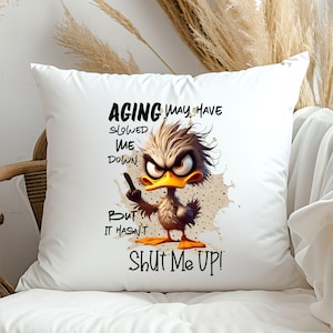May include: White throw pillow with a cartoon duck illustration and the text "AGING may have slowed me down, but it hasn't SHUT ME UP!"