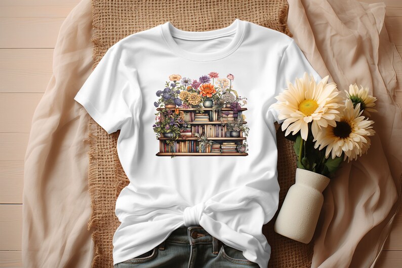 K&ouml;nnte beinhalten: Wei&szlig;es T-Shirt mit einem Motiv einer mit B&uuml;chern gef&uuml;llten B&uuml;cherregals, das mit Blumen verziert ist. Die Blumen sind in verschiedenen Farben, darunter Lila, Rosa, Orange und Gelb.