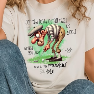 May include: White t-shirt with a cartoon golfer and the text "for the love of all that is good, would you just get in the freakin' hole!"