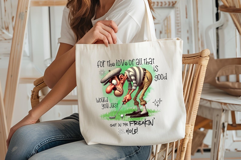 May include: White canvas tote bag with a cartoon golfer illustration and the text "for the love of all that is good, would you just get in the freakin' hole!"