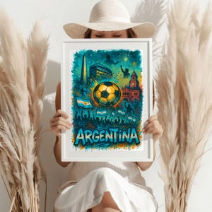 Puede incluir: Una impresi&oacute;n enmarcada en blanco con una ilustraci&oacute;n colorida de un bal&oacute;n de f&uacute;tbol, fuegos artificiales y la palabra "ARGENTINA" en estilo graffiti. La ilustraci&oacute;n tambi&eacute;n incluye un edificio, una bandera y personas.