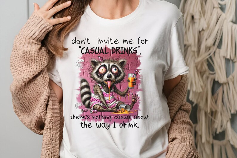 May include: White t-shirt with a cartoon raccoon drinking from a can and the text "don't invite me for "CASUAL DRINKS", there's nothing casual about the way I drink."