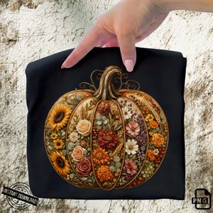 May include: A black t-shirt featuring a large, central graphic of a pumpkin composed of various autumn flowers, including sunflowers, roses, and dahlias in shades of orange, yellow, red, and white, with green foliage and wheat stalks.