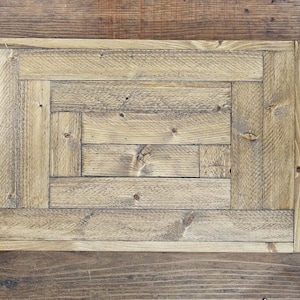 May include: A wooden tray with a rectangular shape and a light brown color. The tray is made of multiple pieces of wood that are arranged in a pattern. The wood has a natural grain and a rustic look.