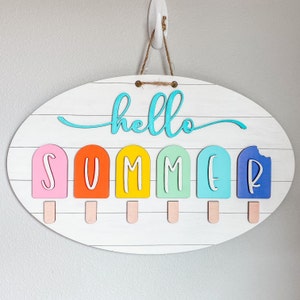 May include: A white oval wooden sign with the words "hello summer" in turquoise blue lettering. The sign has six popsicle-shaped cutouts with the letters "SUMMER" in white lettering. The popsicles are in the colors pink, orange, yellow, green, blue, and purple.