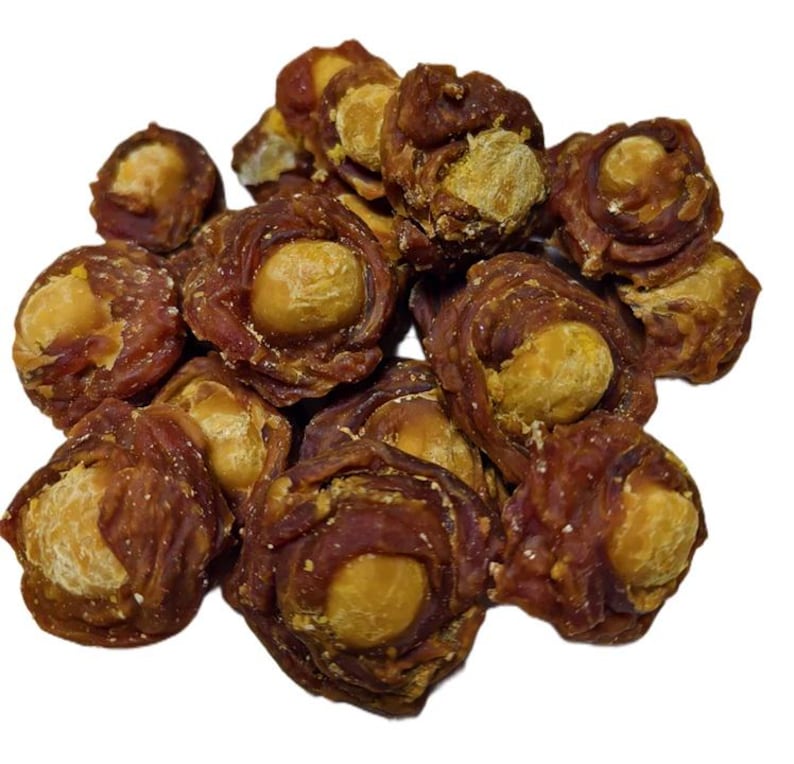 May include: A pile of dog treats, each featuring a light brown center surrounded by a darker brown, textured outer layer. The treats are clustered together against a white background, showcasing their individual shapes and textures.