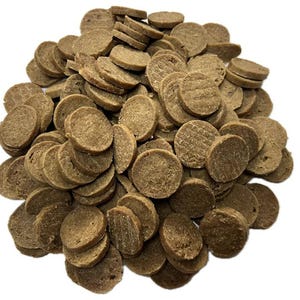 May include: A pile of small, round, brown pet treats. The treats have a slightly textured surface and are stacked in a random arrangement. The treats appear to be dry and are likely a type of dog or cat food.