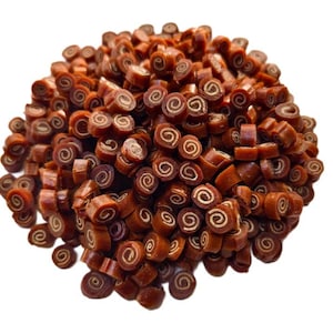 May include: A pile of brown, spiral-shaped dog treats. Each treat has a dark brown exterior and a lighter, tan-colored interior, resembling a cinnamon roll. The treats are scattered against a white background.