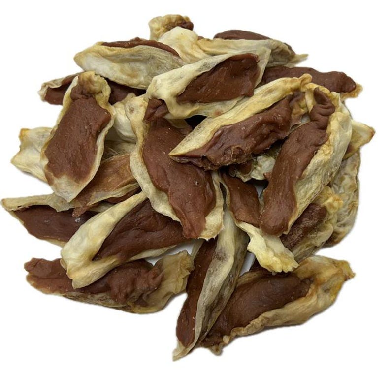 May include: A pile of dog treats, featuring a light tan outer layer and a dark brown filling. The treats have a unique shape, resembling small, open pockets. The background is plain white, highlighting the treats.
