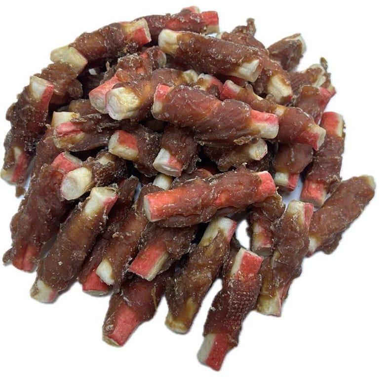 May include: A pile of dog treats. The treats are a dark brown color, with a red and white center. The treats are wrapped in a spiral shape.