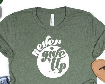 May include: A green t-shirt with a white circle graphic that says "never give up" in a stylized font.
