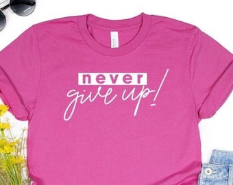 May include: A pink t-shirt with the text "never give up!" printed in white on the front.