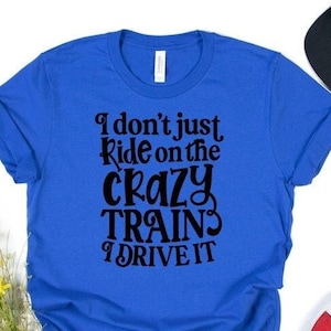 May include: A royal blue t-shirt with black text that reads "I don't just ride on the crazy trains I drive it".