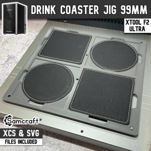 May include: A gray 99mm drink coaster jig for the xTool F2 Ultra laser machine. The jig features four recessed slots holding two square and two circular black coasters with white stitched edges. Text includes DRINK COASTER JIG 99MM, XTOOL F2 ULTRA, and Samcraft.