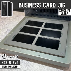 Könnte beinhalten: Eine graue Visitenkarten-Vorlage mit sechs rechteckigen Schlitzen. Der Text "BUSINESS CARD JIG" steht oben, darunter "XTOOL F2 ULTRA". Ein kleines schwarzes Gerät befindet sich in der oberen linken Ecke. Der Text "XCS & SVG FILES INCLUDED" steht unten.