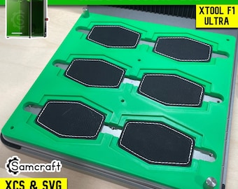 May include: A bright green hex patch jig for the xTool F1 Ultra laser machine. The jig features six hexagonal cutouts holding black leather patches with white stitching. Text on the image includes HEX PATCH JIG, XTOOL F1 ULTRA, and Samcraft XCS & SVG FILES INCLUDED.