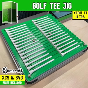 May include: A green golf tee jig with white golf tees arranged in rows. The text "GOLF TEE JIG" is at the top. The text "XTOOL F1 ULTRA" is in a yellow box. The text "Samcraft" and "XCS & SVG FILES INCLUDED" are also visible.
